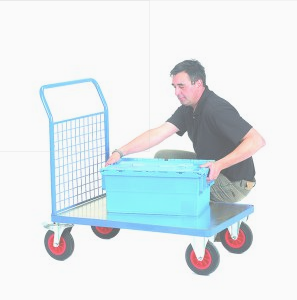 Man squats beside a hand truck trolley as he lifts a heavy toolbox from it
